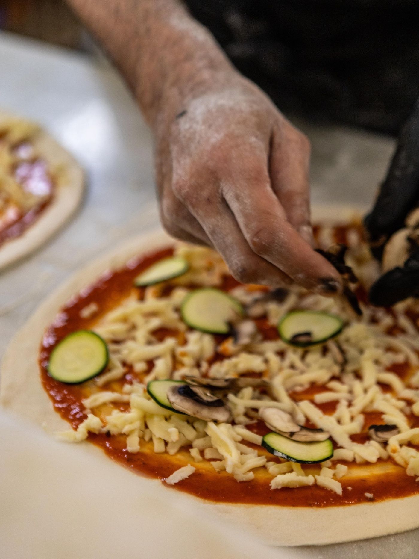 Pizza artesanal a ser preparada com courgette e cogumelos no Bambino Pool Club